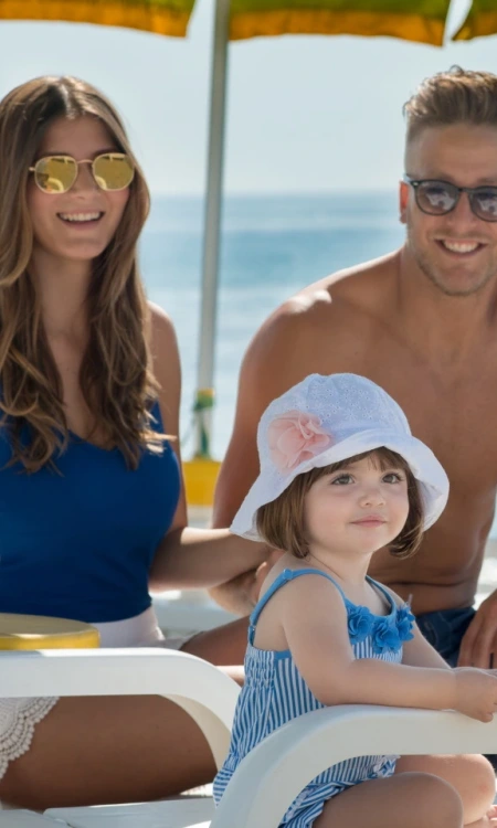 Famiglia felice in spiaggia, sotto l'ombrellone, godendo una giornata di sole.